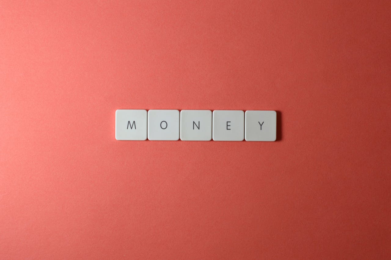 Minimalist layout showing word 'money' with letter tiles on a coral background.